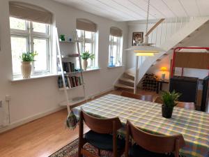 a dining room with a table and a staircase at Det lille røde hus in Nyord