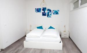 una camera bianca con letto bianco e cuscini blu di Loft 82 Apartments a Bolzano