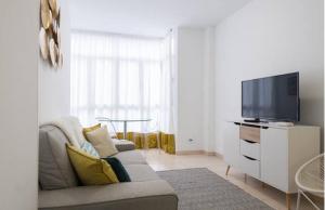 ein Wohnzimmer mit einem Sofa und einem Flachbild-TV in der Unterkunft Stylish apartment in Canteras beach in Las Palmas de Gran Canaria