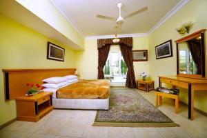 Muscat International Hotel في مسقط: غرفة نوم بسرير ومكتب وبيانو
