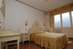 a bedroom with a bed and a desk and a window at Hotel Villa Margherita in Limone sul Garda