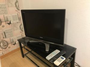 een tv op een tafel met twee afstandsbedieningen bij AK301 Guest house AKASAKA in Fukuoka