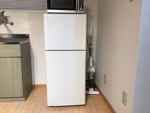 een witte koelkast met een magnetron erop bij AK301 Guest house AKASAKA in Fukuoka