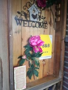 una porta con un cartello di benvenuto e una rosa rosa di La Rose a Overpelt