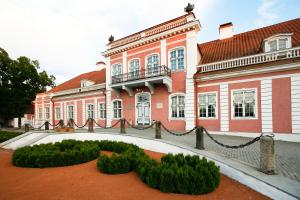 um grande edifício rosa com arbustos à sua frente em Sagadi Manor Hostel em Sagadi