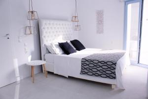 a white bedroom with a large white bed with black pillows at Aegean of Amorgos in Katapola
