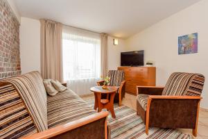 a living room with two couches and a tv at Kubu Apartment in Klaipėda