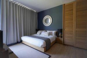 una camera da letto con un letto e uno specchio a parete di Baan Mai Khao a Mai Khao Beach