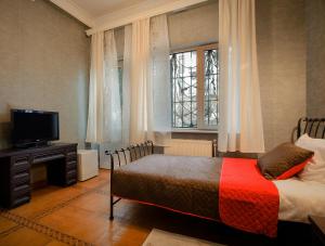 a bedroom with a bed and a tv and window at Hotel Toma's House in Tbilisi City
