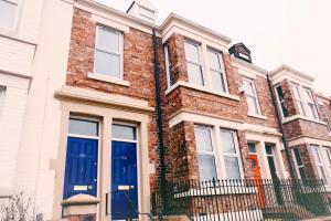 a brick house with blue doors on a street at Coalminer's Cottage in Gateshead
