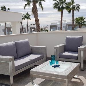 a patio with two couches and a table and palm trees at Sensación Azul in Torrevieja