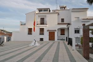 a white building with a flag in front of it at Casa La Plaza in Frigiliana