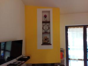 un soggiorno con parete gialla e TV di Casa Vacanza Clavel a Sirmione