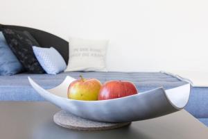 two apples in a bowl on a table next to a bed at Refugium 1 in Emsdetten