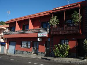 a red building with a balcony on a street at Apartamentos Los Volcanes in Fuencaliente de la Palma