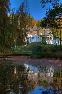 una casa se refleja en un cuerpo de agua en Parkhotel Villa des Effats Vielsalm, en Vielsalm