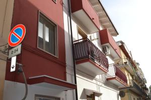 a red building with balconies and a no parking sign at Planet apartments 1 in Montalbano Jonico