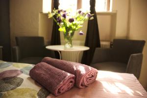 una mesa con dos toallas y un jarrón de flores en Rosemary's Private Ensuite Rooms in Old Town, en Poznan