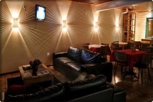 uma sala de estar com um sofá de couro e uma sala de jantar em Pousada Solar dos Guaras em Catas Altas