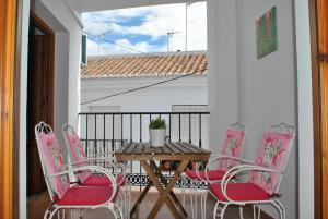 a wooden table and four pink chairs on a balcony at Casa La Plaza in Frigiliana