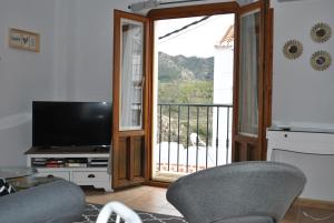 a living room with a television and a balcony at Casa La Plaza in Frigiliana
