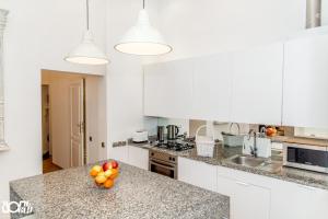 una cucina con armadi bianchi e un cesto di frutta su un bancone di P&J Apartments Floriańska a Cracovia