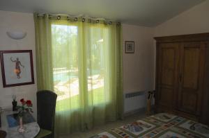 エギユにあるun lit en provenceのベッドルーム1室(緑のカーテン付きの窓付)