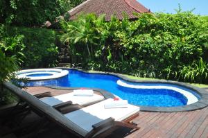 a swimming pool with two lounge chairs next to a swimming pool at The Zen Villas in Sanur