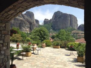 an archway with tables and chairs and mountains in the background at Hotel Doupiani House in Kalabaka
