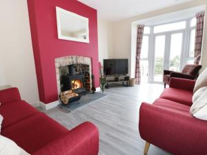 a living room with a fireplace and a red wall at Hillside Cottage in Prestatyn