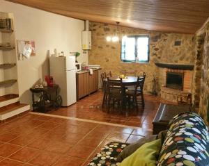 a kitchen and a living room with a table and a refrigerator at Casas da Lagoa - 4 Casas de Férias Independentes in Santo Isidoro