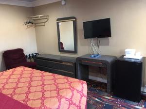 Zimmer mit einem Bett, einem TV und einem Spiegel in der Unterkunft Budget Inn LAX-Lawndale in Lawndale