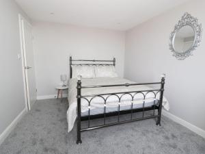 a bedroom with a black bed and a mirror at Hillside Cottage in Prestatyn