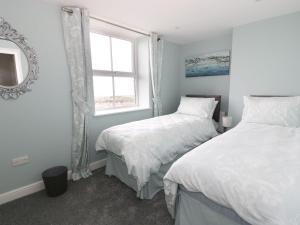 a bedroom with two twin beds and a window at Hillside Cottage in Prestatyn