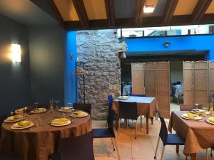 comedor con mesas y sillas y pared de piedra en Hotel Torrepalacio en Proaza