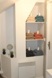 a bathroom with a shelf with towels and a fan at Le Ch'ti Champenois in Épernay +25 photos
