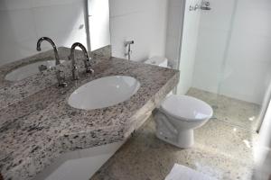 a bathroom with two sinks and a toilet at Hotel Cosini in São Sebastião do Paraíso