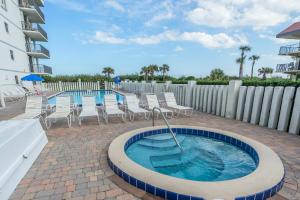 a swimming pool with chairs and a hot tub at Cape Winds in Cape Canaveral