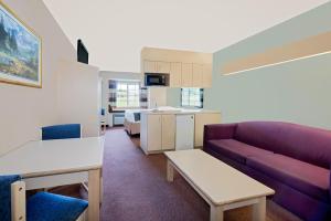 a living room with a purple couch and a kitchen at Microtel Inn & Suites by Wyndham Joplin in Joplin