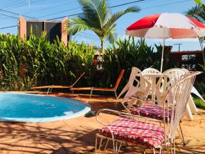 a group of chairs and an umbrella next to a pool at Pousada Recanto Domus in Ubatuba