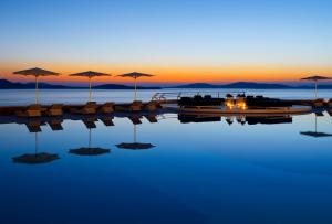 a pool with chairs and umbrellas in the water at Mykonos Grand Hotel & Resort in Agios Ioannis Mykonos +74 photos