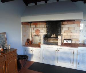 a kitchen with a brick fireplace with white cabinets at Casa dos Salgueiros in Faja Grande