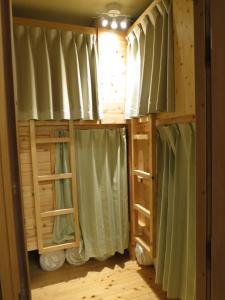 東京にあるノーボーダーズ ホステルの二段ベッド(緑のカーテン付)が備わる客室です。