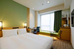 ein Hotelzimmer mit einem großen Bett und einem Schreibtisch in der Unterkunft Candeo Hotels Tokyo Shimbashi in Tokio