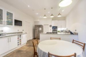 een witte keuken met een tafel en stoelen. bij JOIVY Spacious 2 Bed Apt in Ideal City Centre Location in Edinburgh
