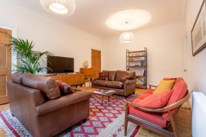 een woonkamer met lederen meubels en een televisie bij JOIVY Spacious 2 Bed Apt in Ideal City Centre Location in Edinburgh