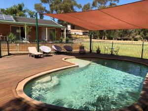 a swimming pool with an umbrella on a deck at Bullanginya Lodge in Barooga