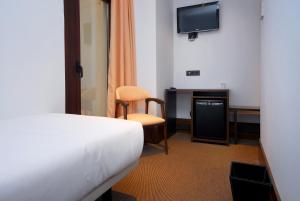 um quarto de hotel com uma cama e uma televisão em Hotel Domus Plaza Zocodover em Toledo