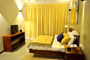 a bedroom with a bed with yellow pillows and a television at Kethaka Aga in Tissamaharama