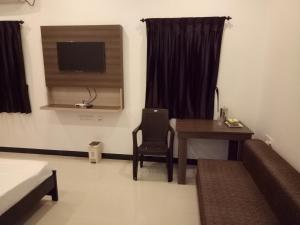 a room with a desk and a table and a television at ComfortWings in Coimbatore